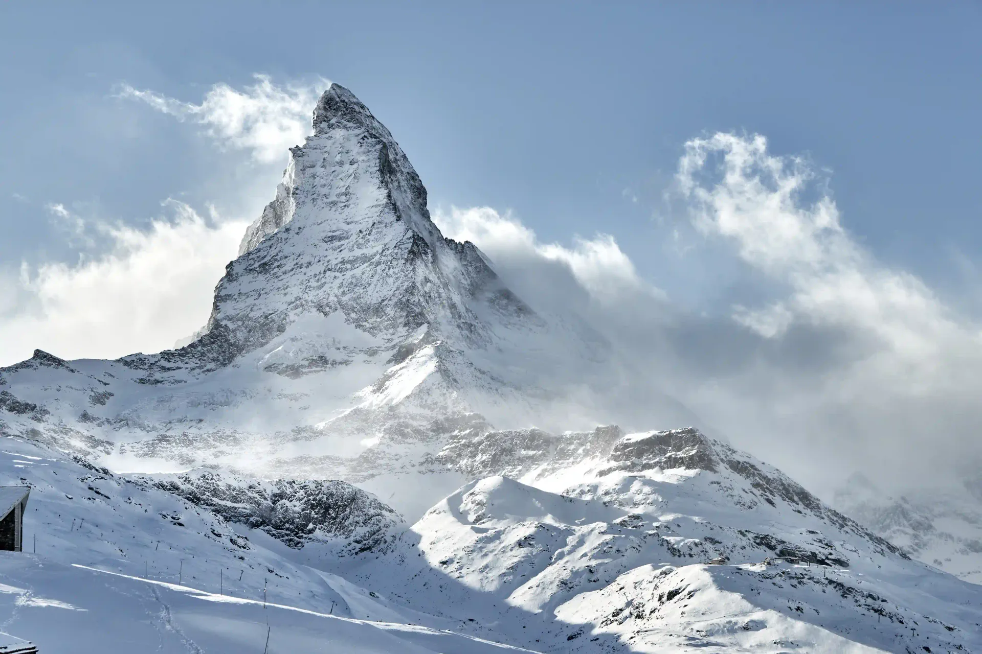 Una vista maestosa del Cervino innevato sotto un cielo azzurro parzialmente nuvoloso.